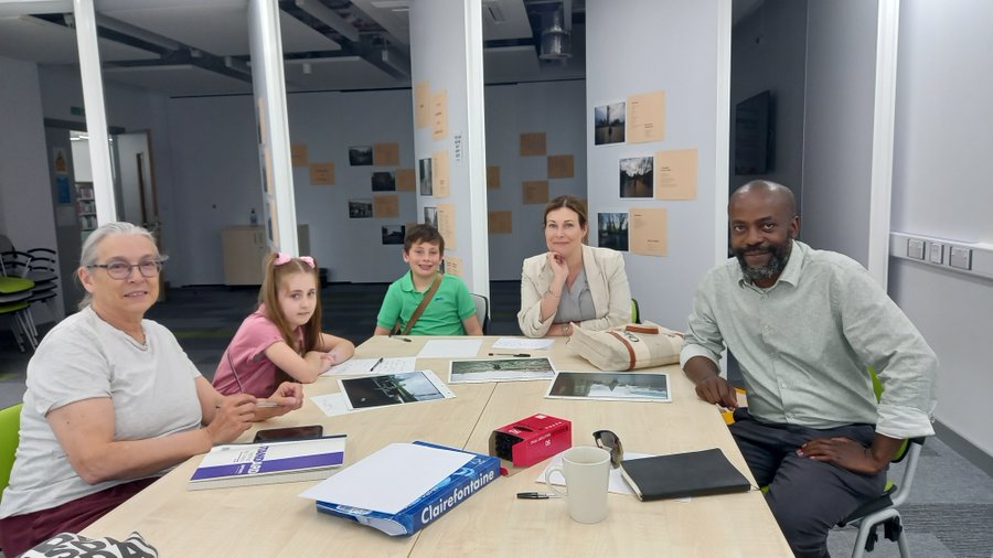Two adults and two children attending a workshop with an exhibition in the background